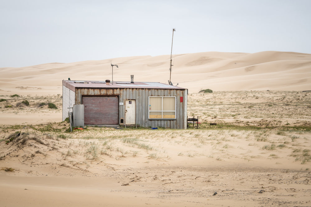 Seven Seven South West at Tin City, shack number seven sits alone against a wall of sand dunes that rises behind it like.