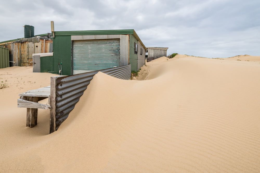 The Outskirts at Tin City, sand dunes press against corrugated iron sheds on the outer edge of Tin City.