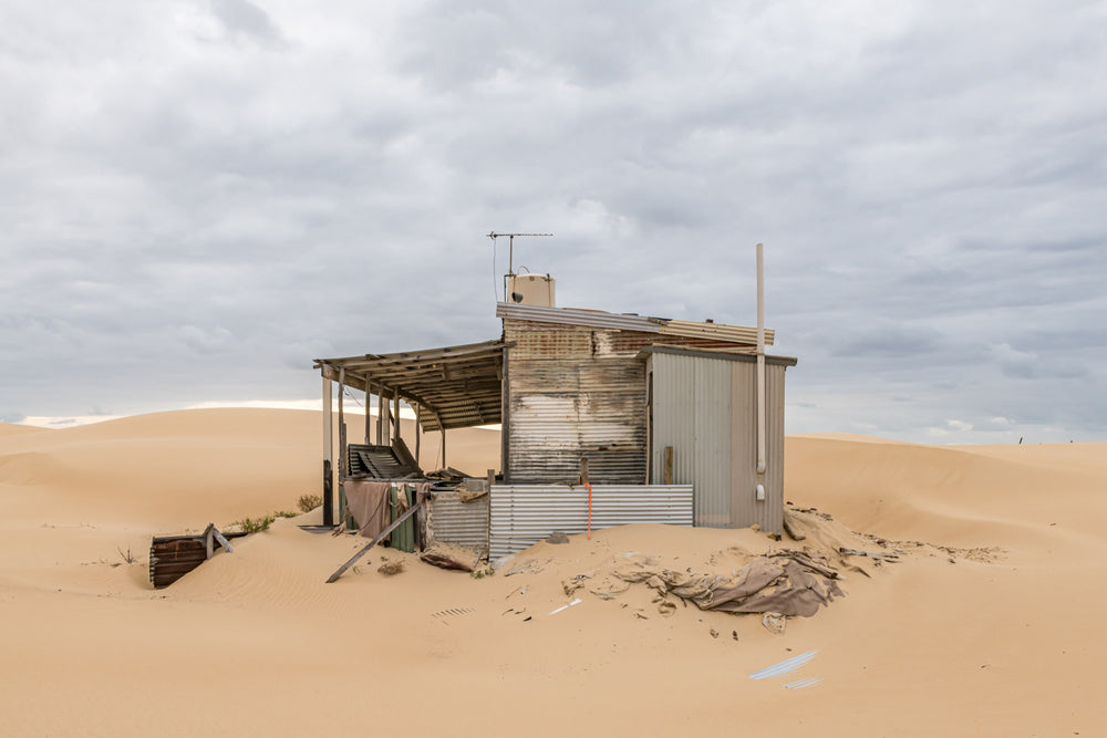 The Porch at Tin City, a corrugated iron shack sits half-swallowed by sand.
