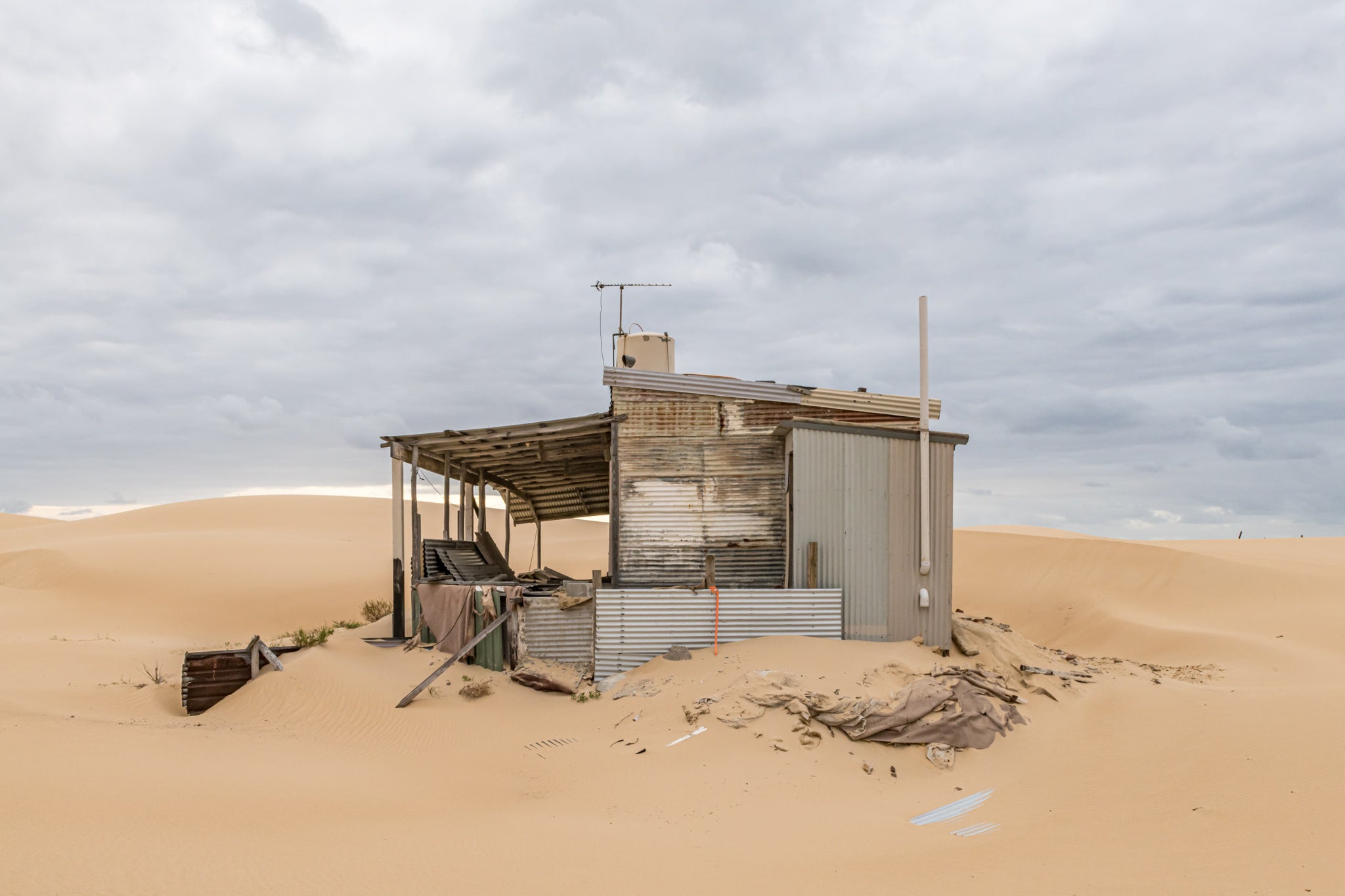 The Porch at Tin City, a corrugated iron shack sits half-swallowed by sand.