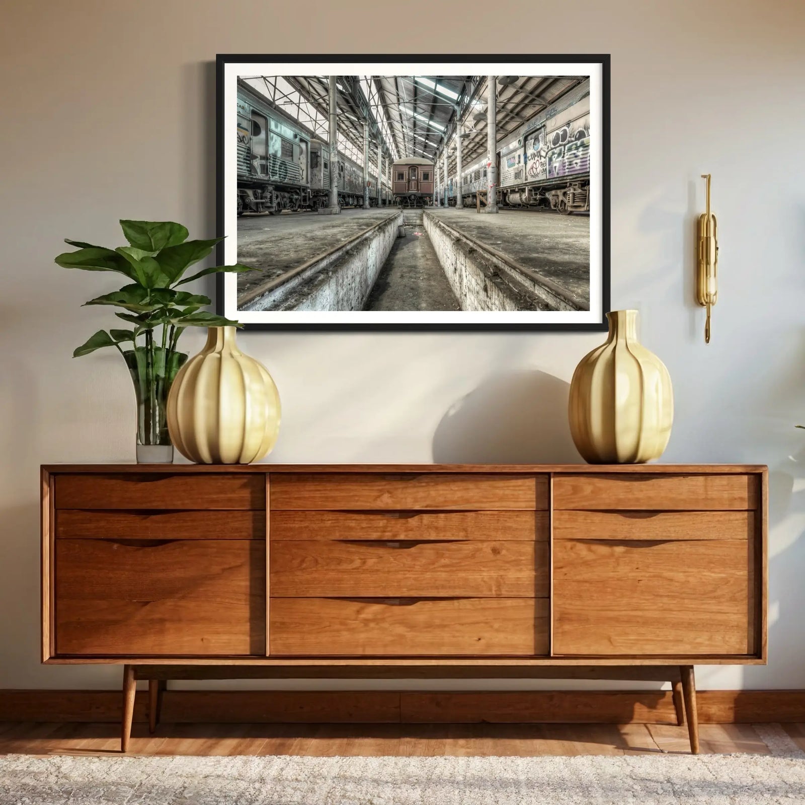Minimalist living room with a large framed art print showcasing an abandoned train depot above a wooden console table.