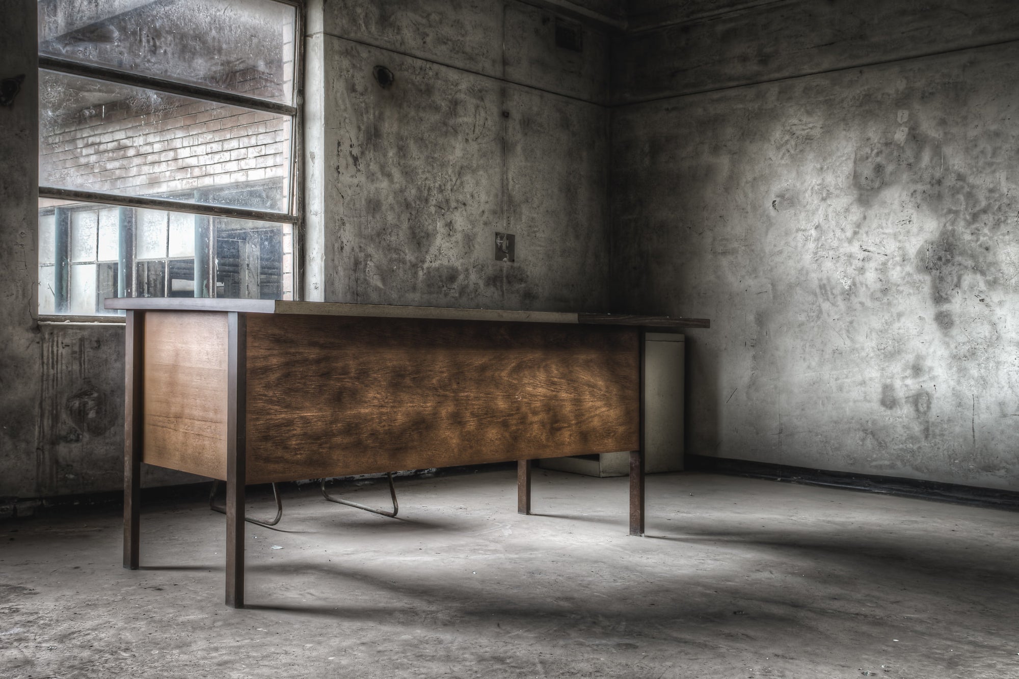 Office Desk at Wangi Power Station, a timber veneer desk sits alone in a concrete room.