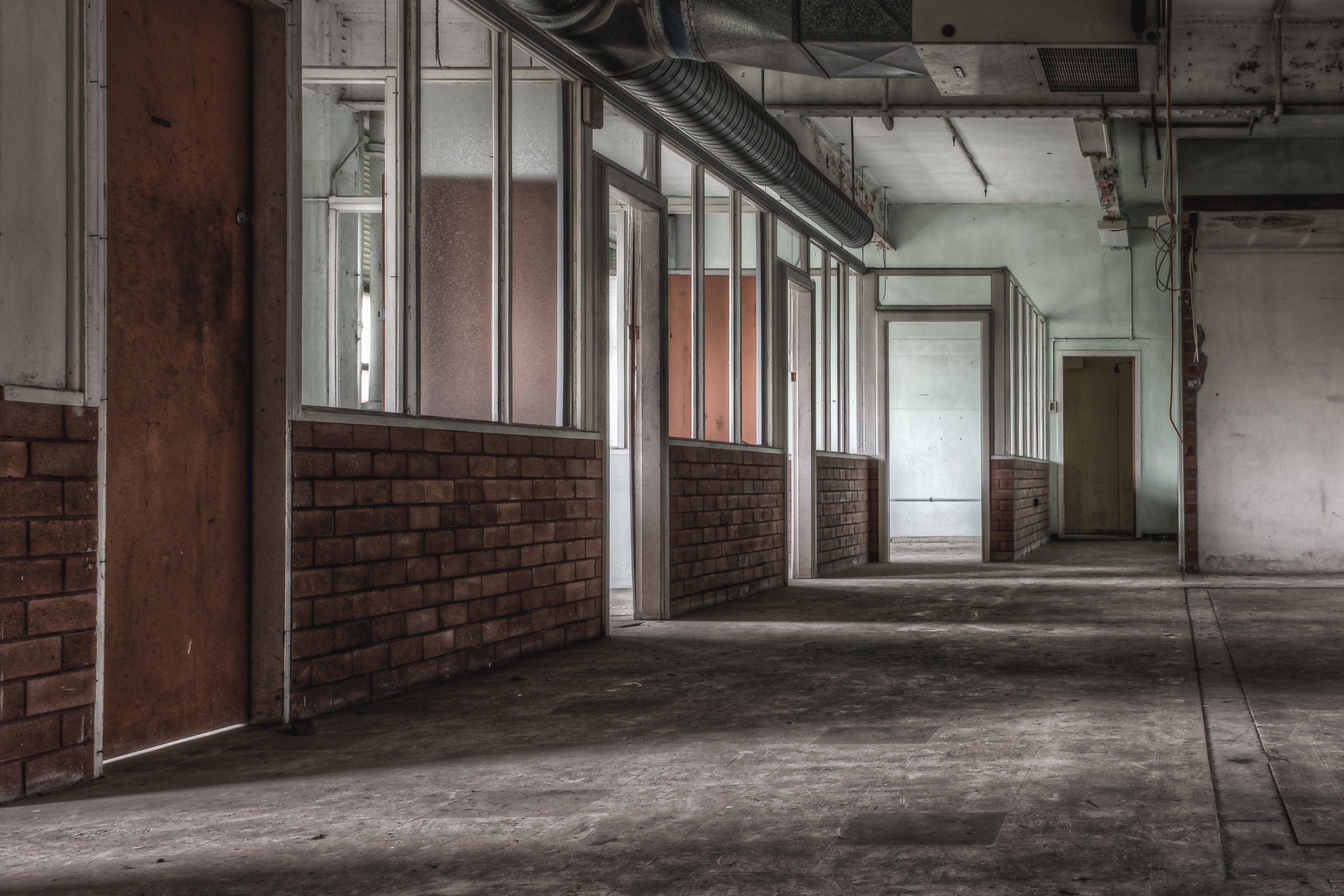 Training Section Offices at Wangi Power Station, a row of partitioned offices lines the corridor, brick half-walls topped.