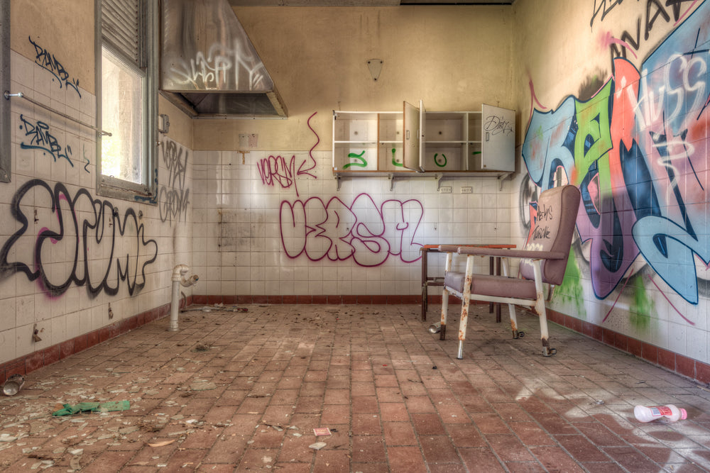 Clinic Chair at Waterfall Sanatorium, a single padded chair sits off-centre on a brick-paved floor, angled toward empty.
