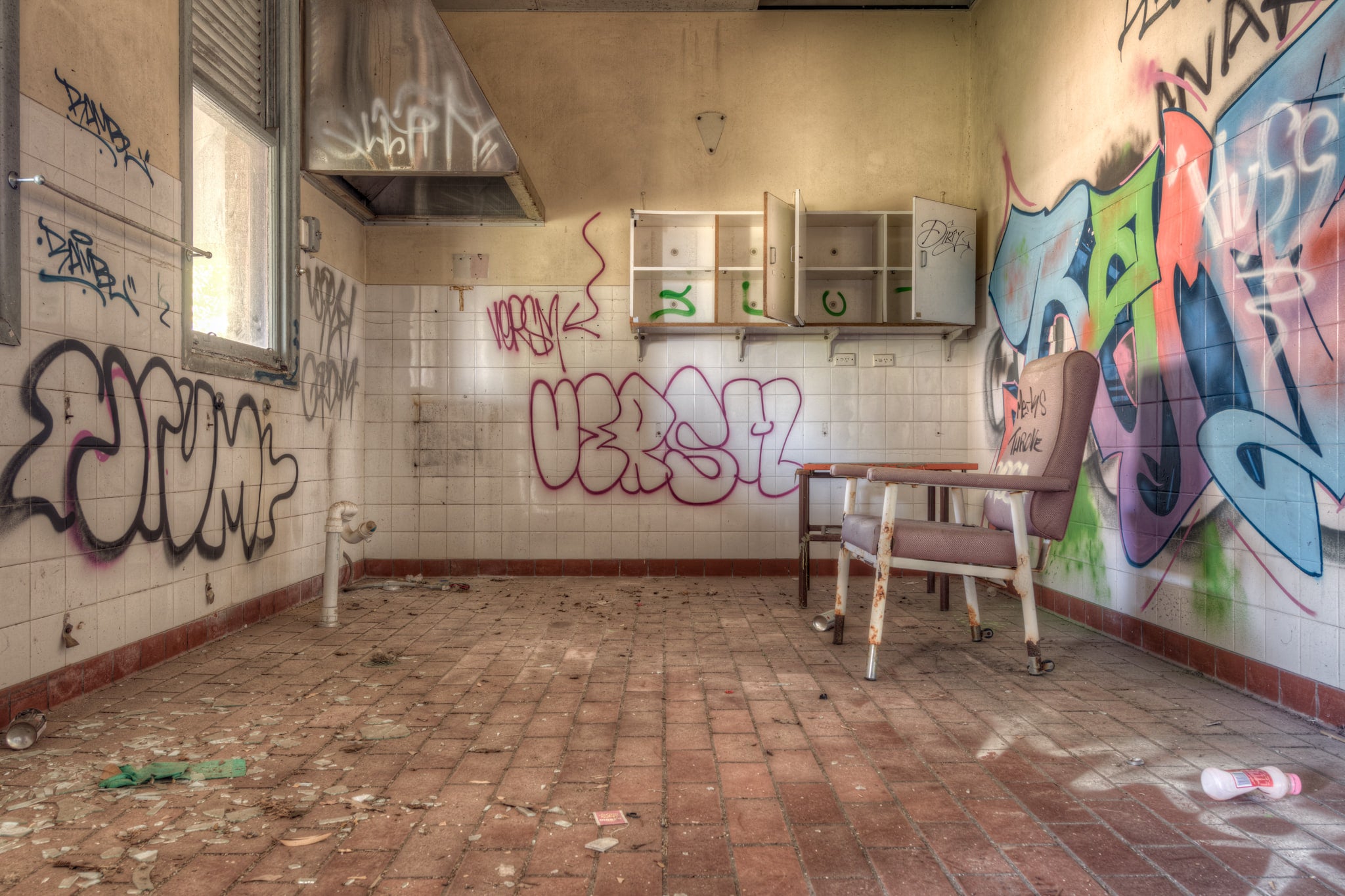 Clinic Chair at Waterfall Sanatorium, a single padded chair sits off-centre on a brick-paved floor, angled toward empty.