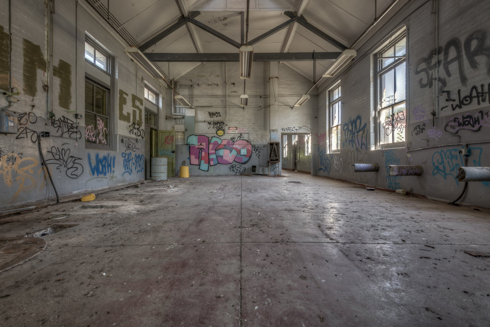 Empty Arches at Waterfall Sanatorium, steel trusses span the pitched ceiling of a long rectangular hall.