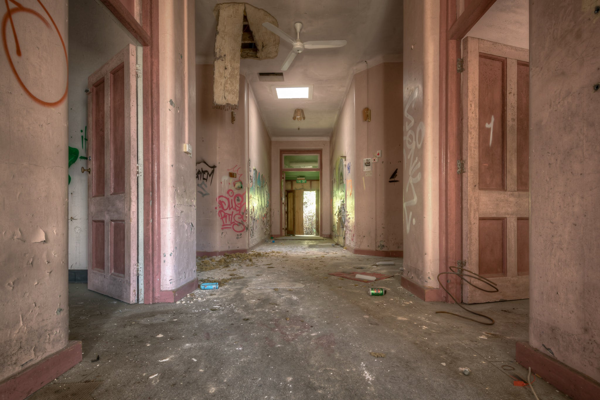 Every Which Way at Waterfall Sanatorium, a corridor runs deep into the building, its pink-painted walls faded to a chalky.