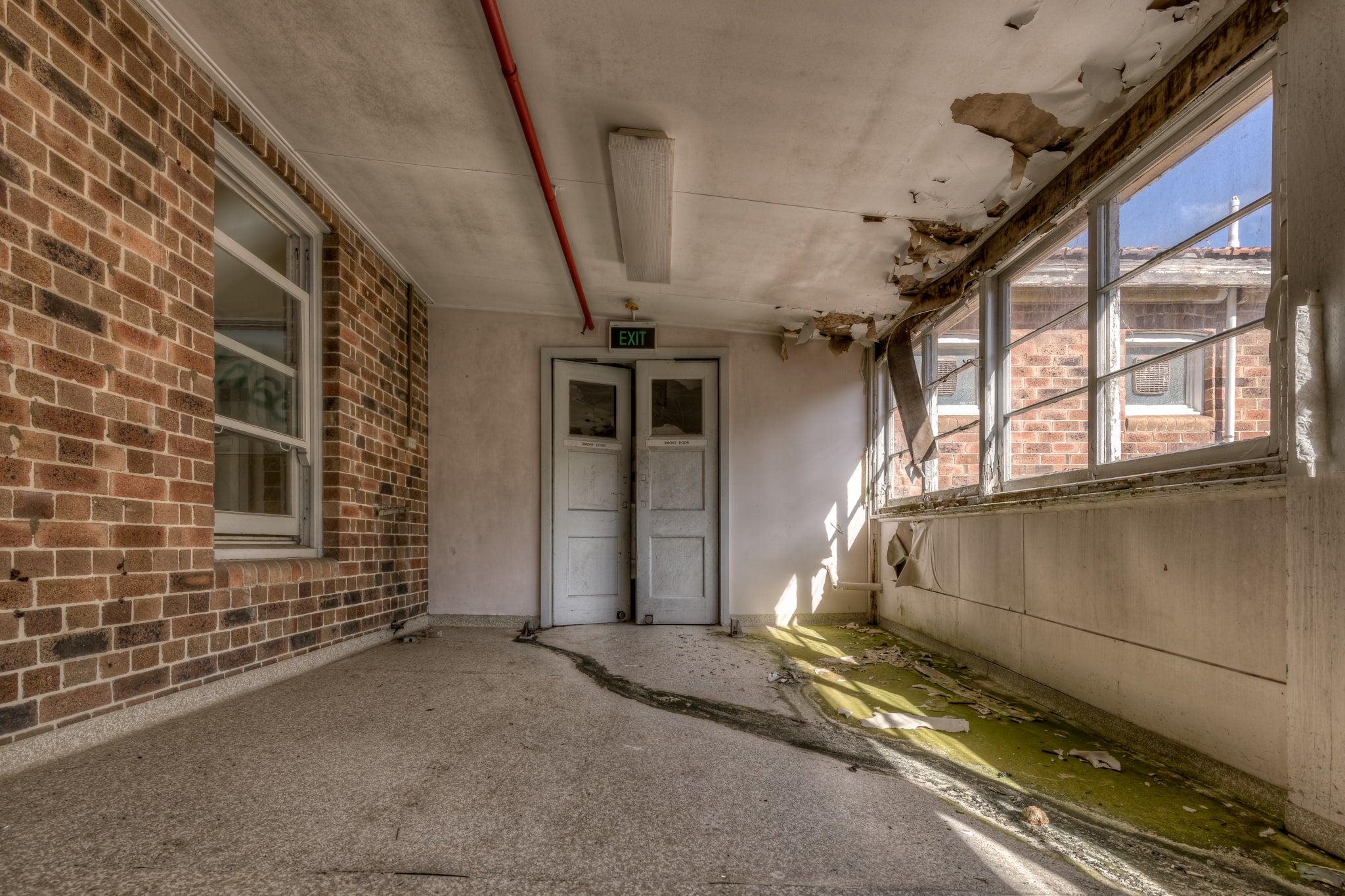 Exit Walkway at Waterfall Sanatorium, an external corridor tinged green closest to the window.
