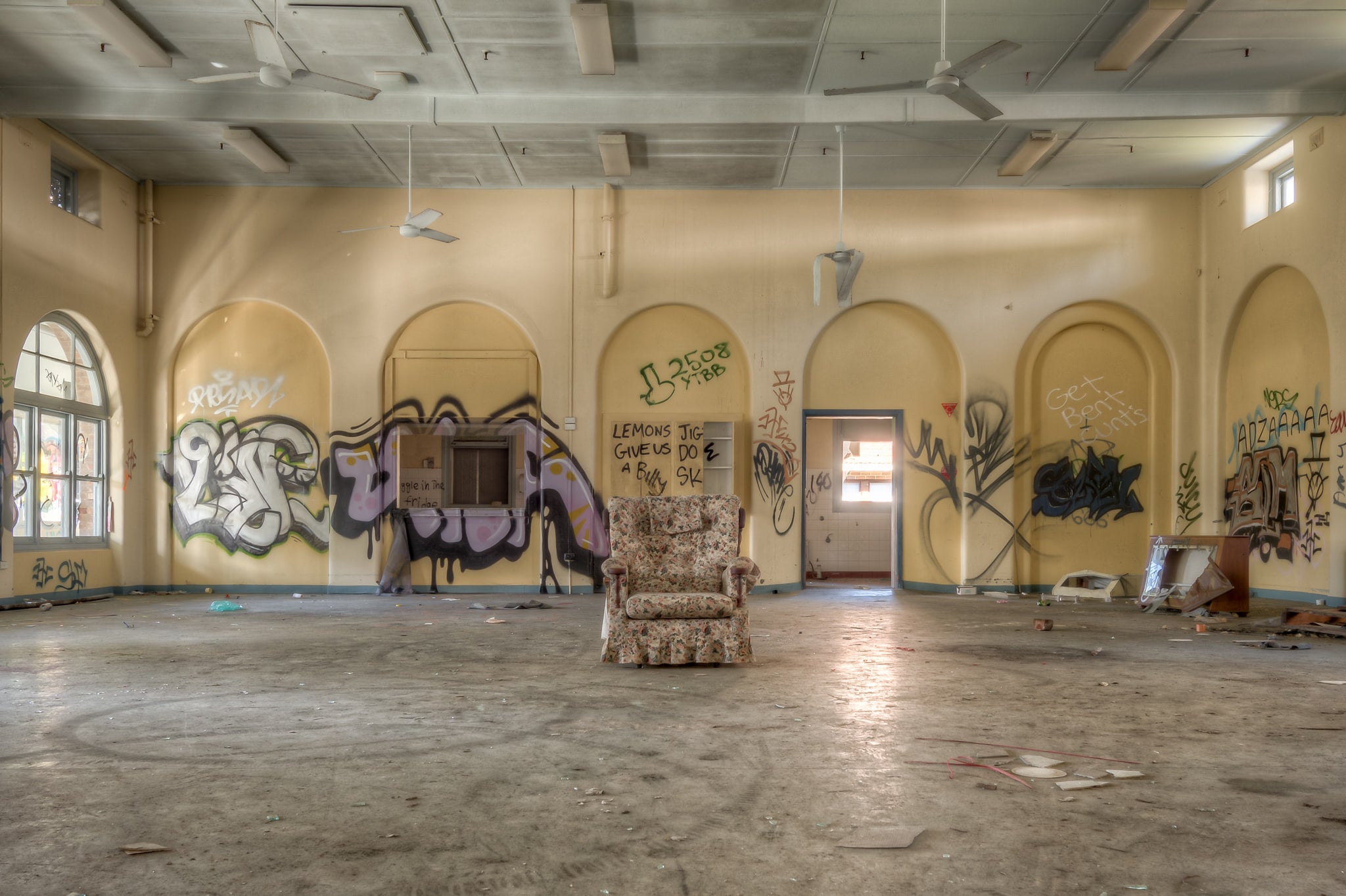 Lone Chair at Waterfall Sanatorium, a floral armchair sits alone at the centre of a large hall.