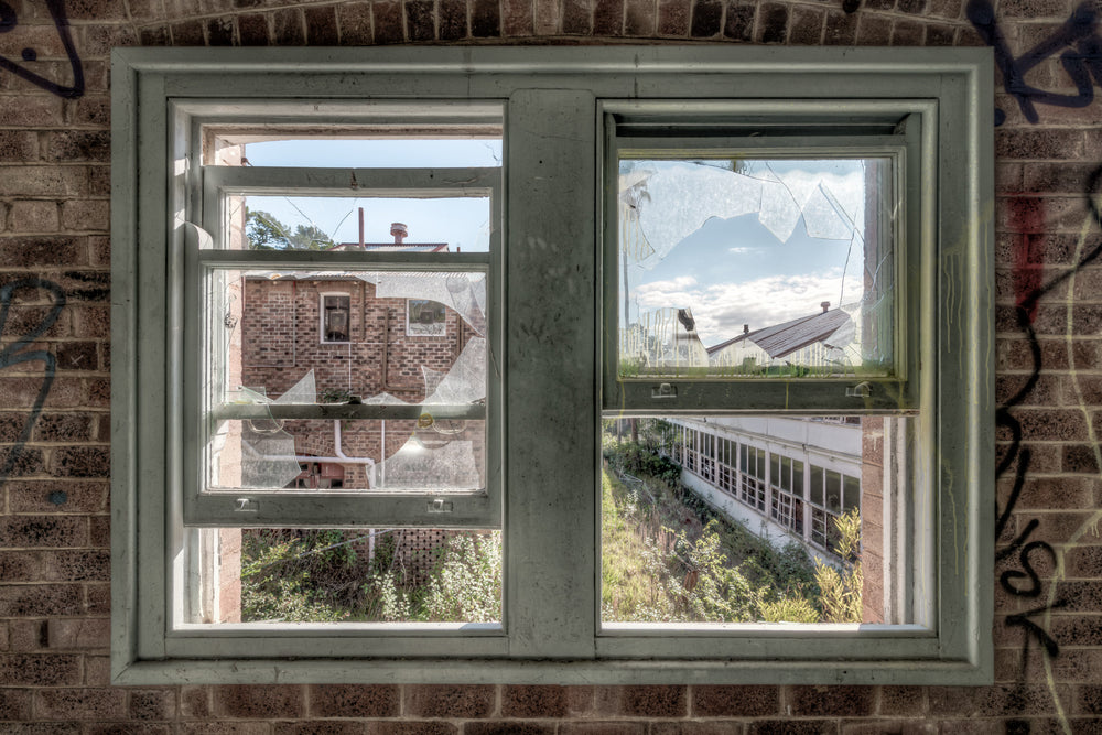 Looking Out at Waterfall Sanatorium, broken windows viewing out towards the overgrown grounds of Waterfall Sanatorium.