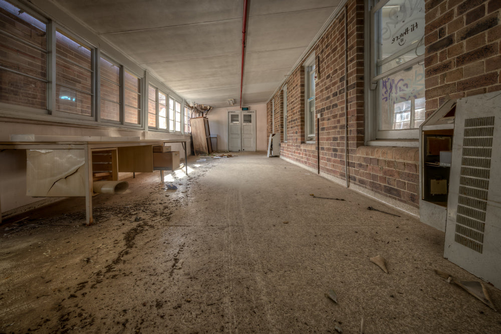 Marbled Lino at Waterfall Sanatorium, a long corridor runs between a brick interior wall and a row of louvred windows.