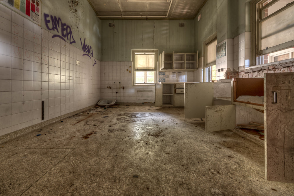 Nothing Left at Waterfall Sanatorium, white ceramic tiles line the left wall, half of them still intact.