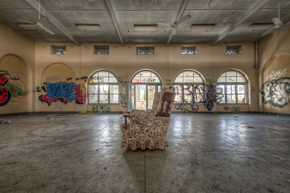 Side Chair at Waterfall Sanatorium, a floral armchair sits alone at the centre of a large hall.