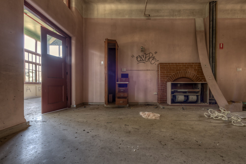 The Fireplace at Waterfall Sanatorium, a brick fireplace sits against the far wall, its arched opening now stuffed.