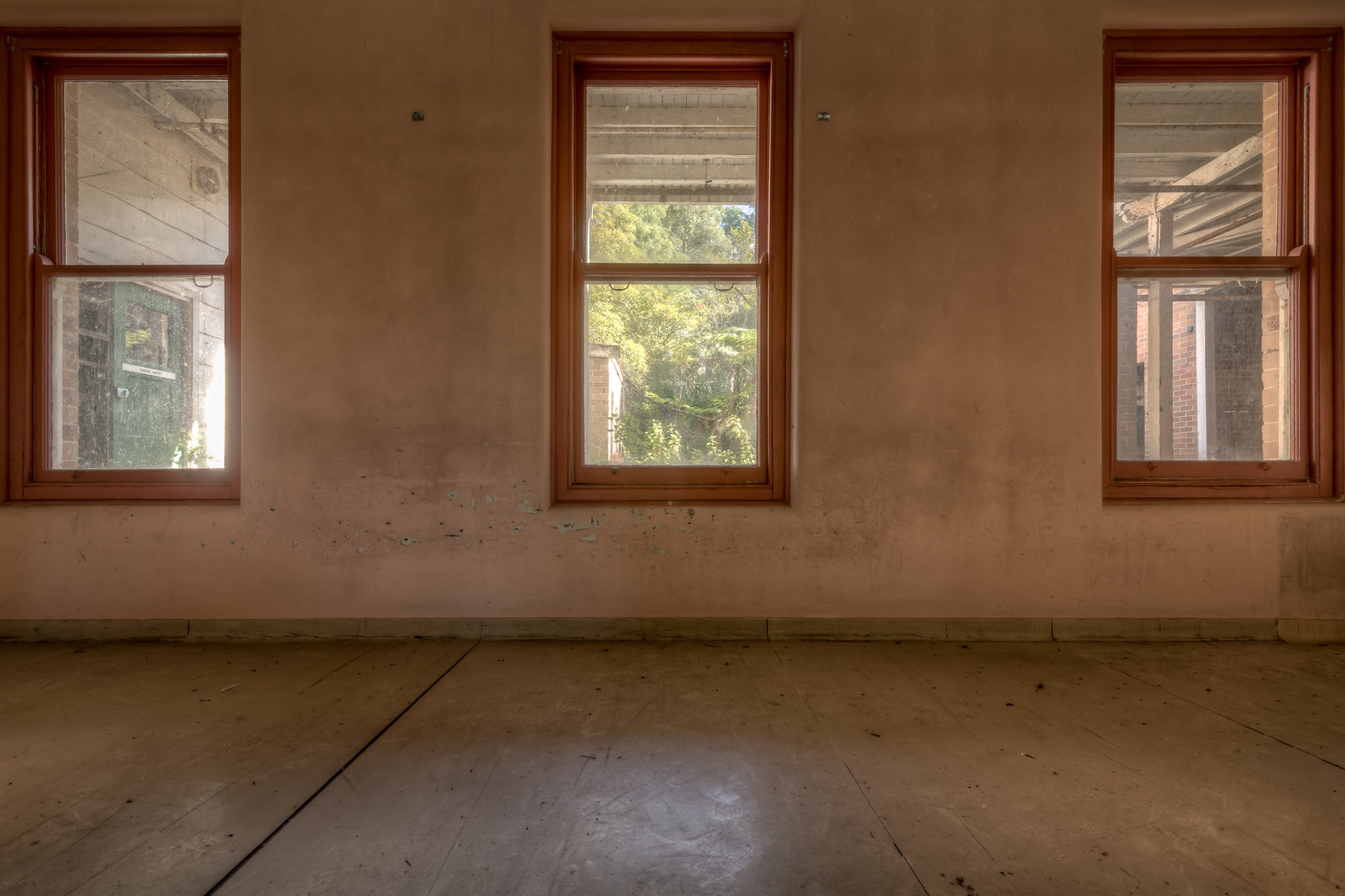 Three Windows at Waterfall Sanatorium, three timber-framed windows sit evenly spaced across a rendered wall.