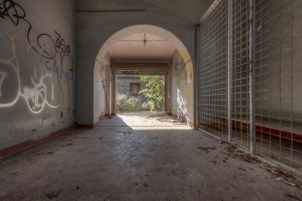 Utility at Waterfall Sanatorium, a caged storage area leading to a roller door exit.