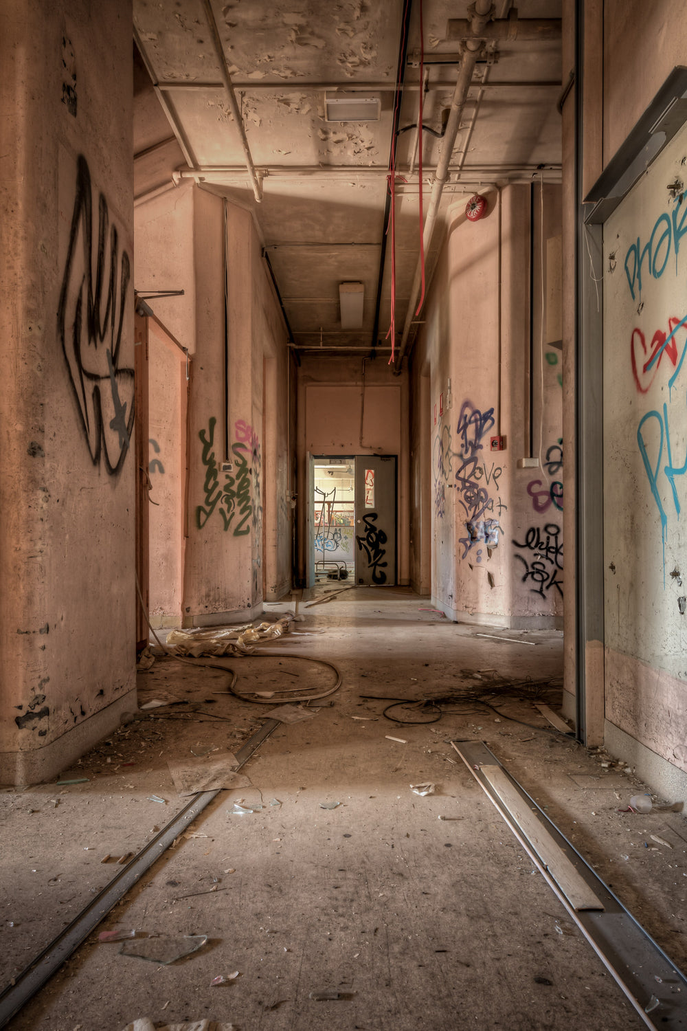 Ward Hall at Waterfall Sanatorium, a corridor stretches toward a single doorway where daylight enters.