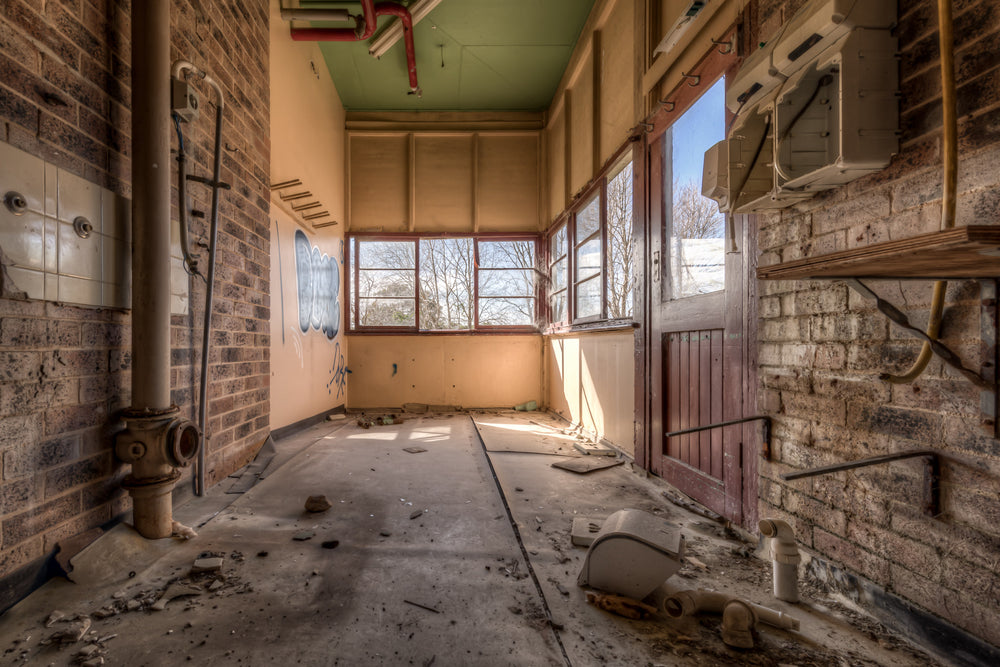 Washroom at Waterfall Sanatorium, a narrow brick corridor opens toward a bank of timber-framed windows.