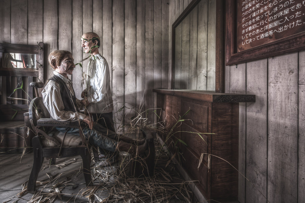 Barber at Western Village, weeds push up through the timber floorboards in the barber shop.