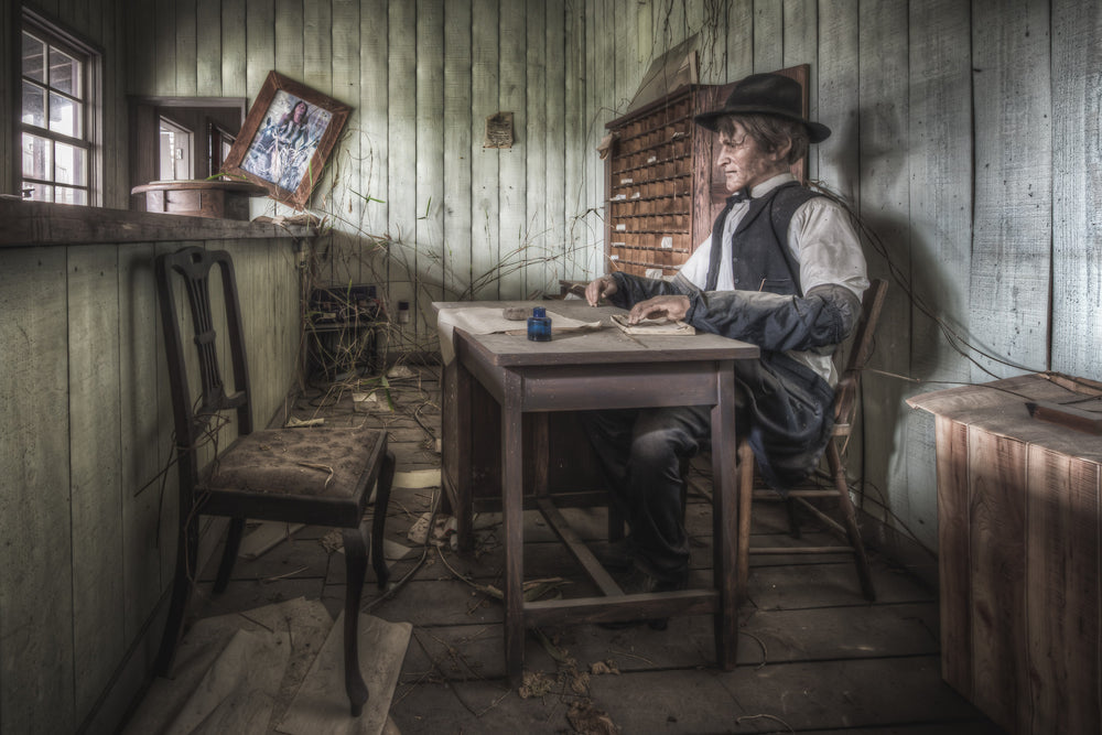 Post Office at Western Village, a wax figure sits at a timber desk inside a small post office recreation.