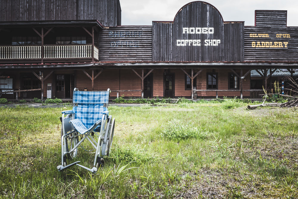 Rodeo Coffee Shop at Western Village, a wheelchair sits on an overgrown lawn in front of the coffee shop.