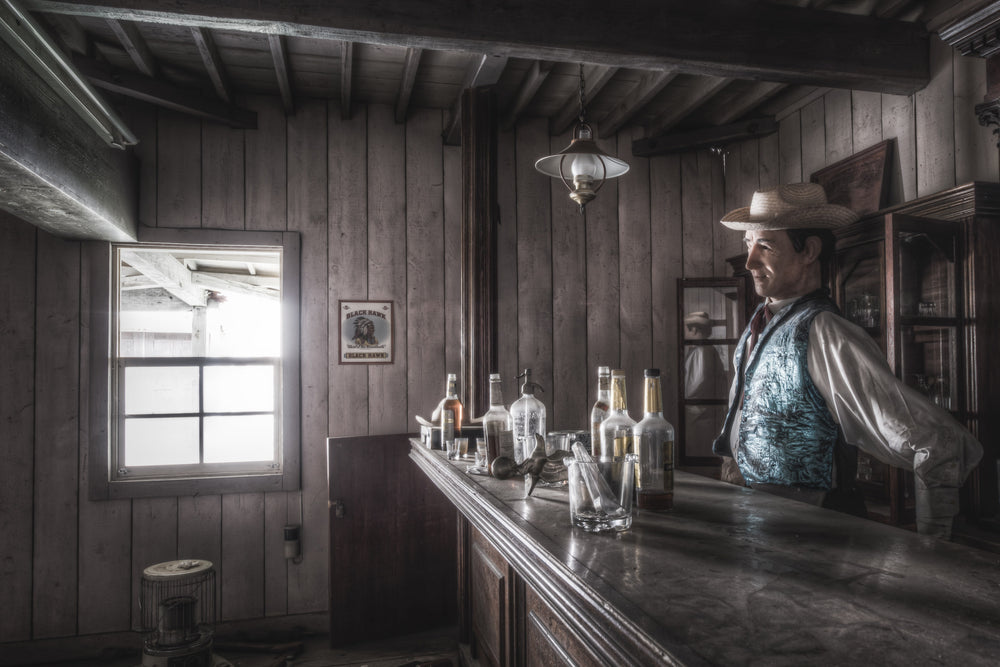 Saloon at Western Village, the bartender of the Western Village saloon stands behind the dimly lit bar.