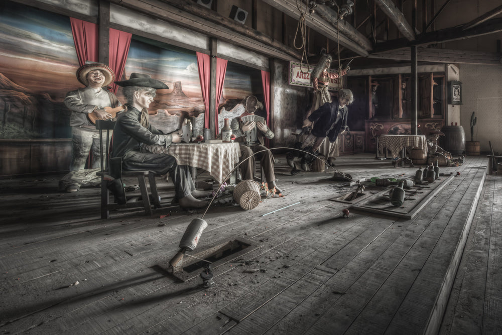 Stageplay at Western Village, animatronic cowboys sit around a checkered tablecloth inside a timber saloon set.