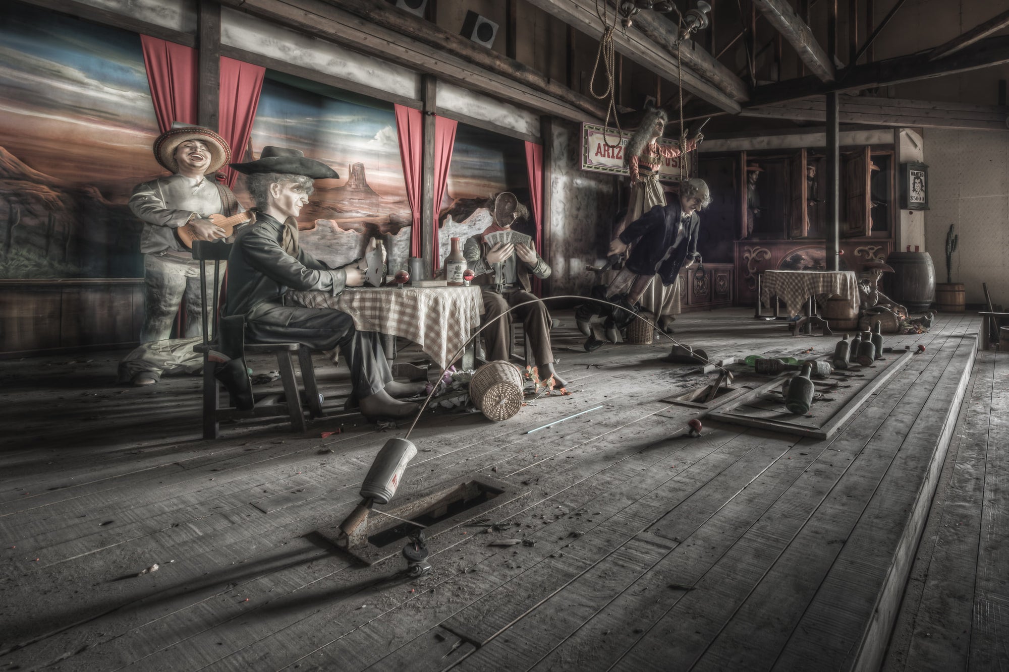 Stageplay at Western Village, animatronic cowboys sit around a checkered tablecloth inside a timber saloon set.
