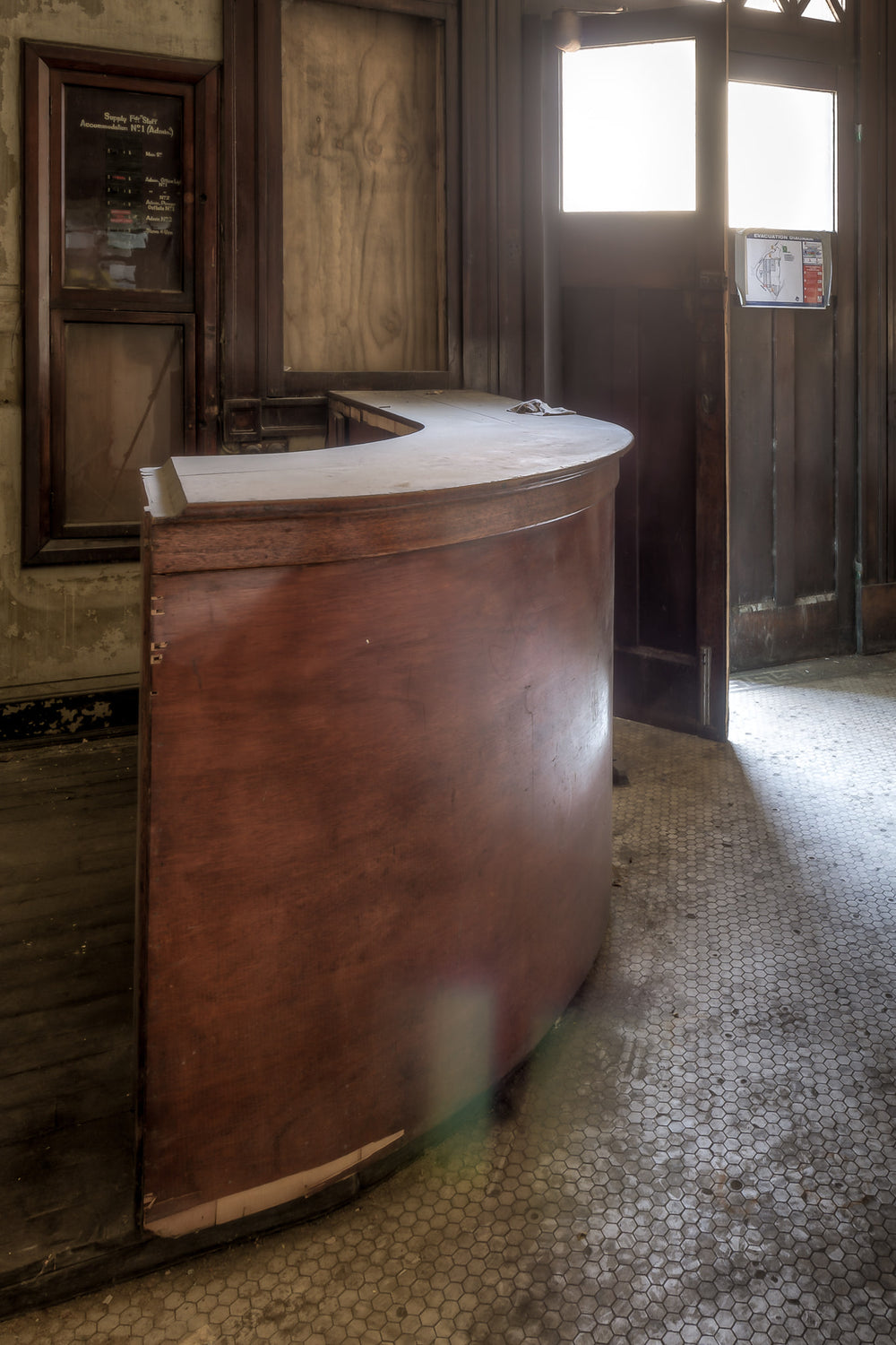Receptionists Desk at White Bay Power Station, a curved timber reception desk sits on a floor of white hexagonal mosaic.