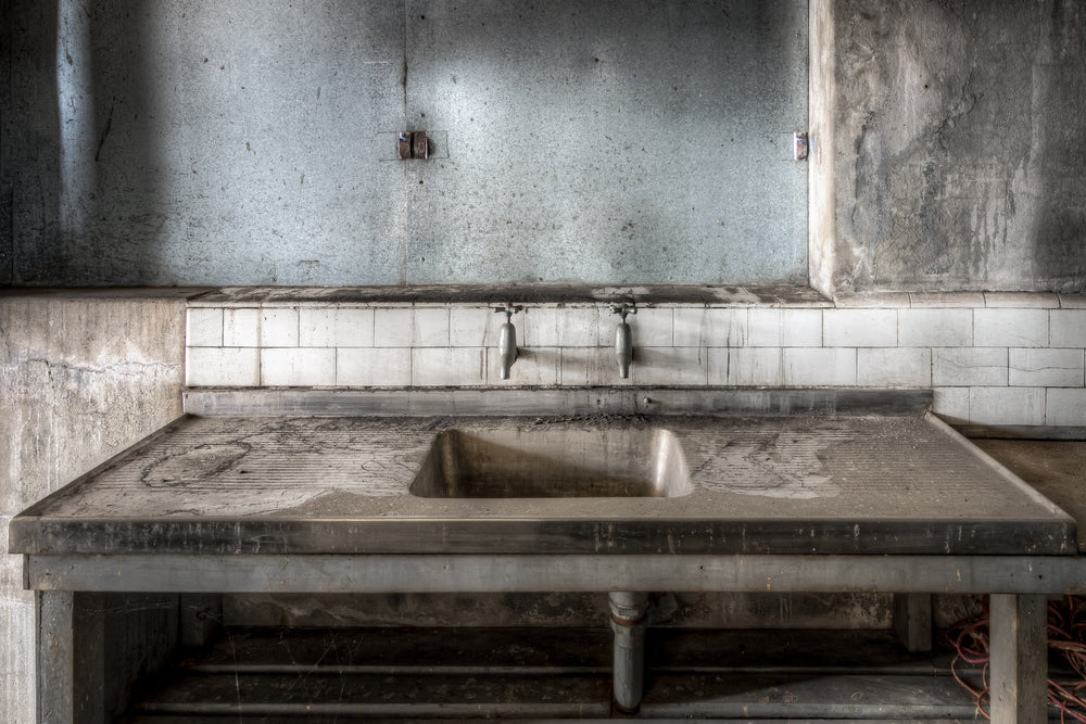 Sink at White Bay Power Station, a stainless steel sink sits square in the frame, its draining boards thick with grey dust.