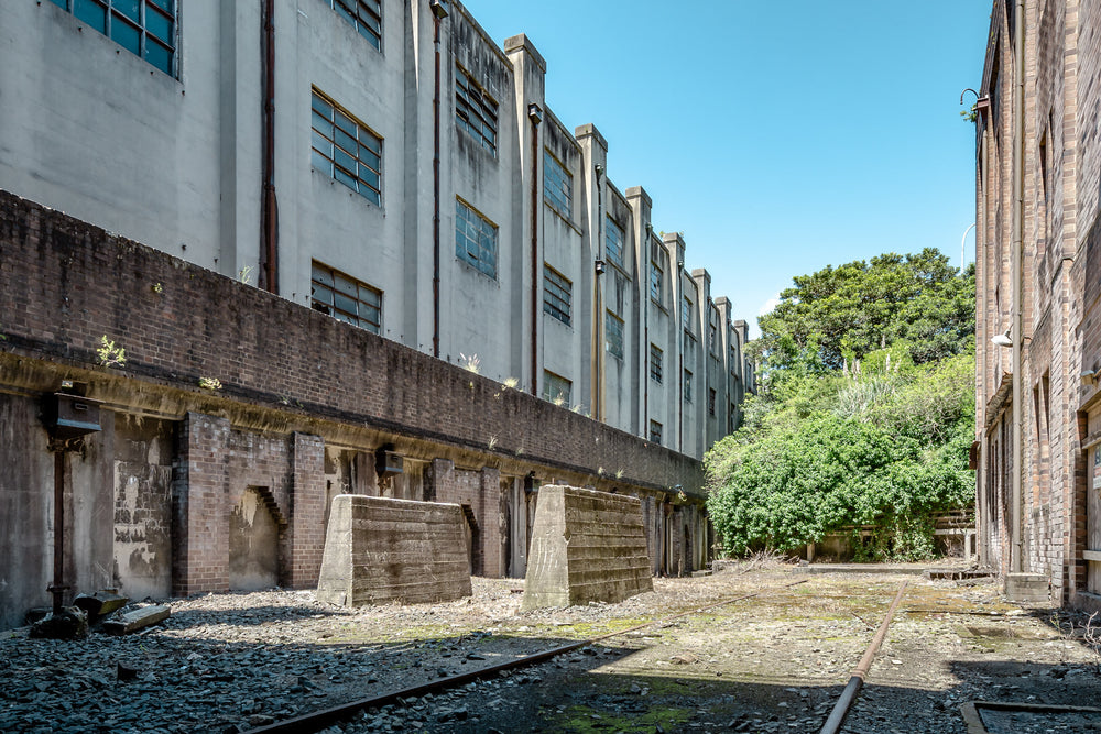South West Transformer Yard at White Bay Power Station, rail lines run between two industrial buildings, half-buried.