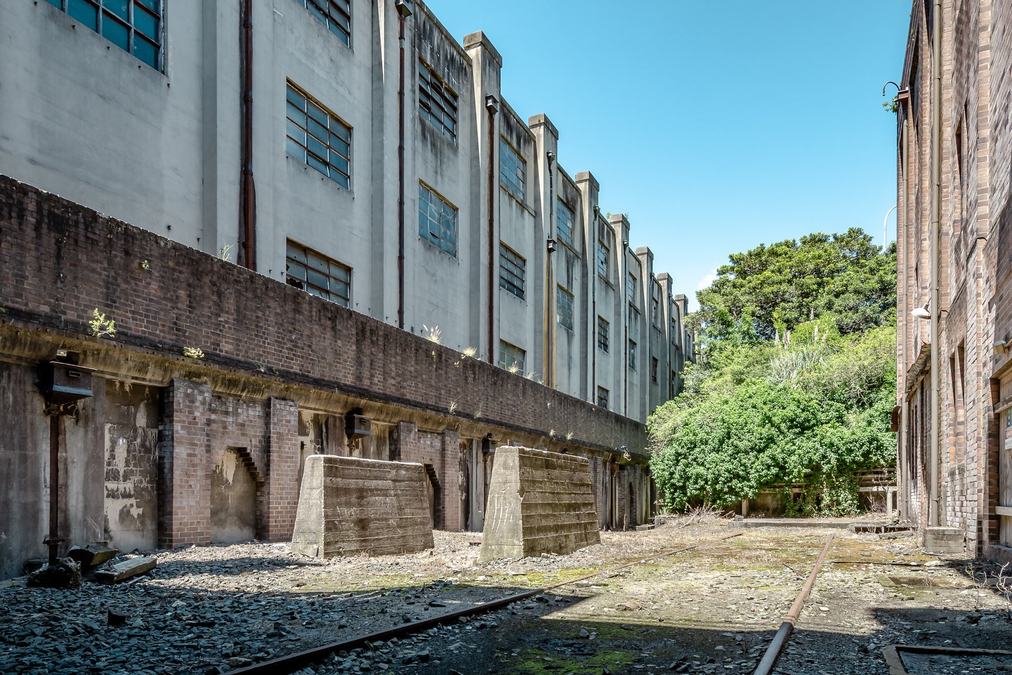 South West Transformer Yard at White Bay Power Station, rail lines run between two industrial buildings, half-buried.