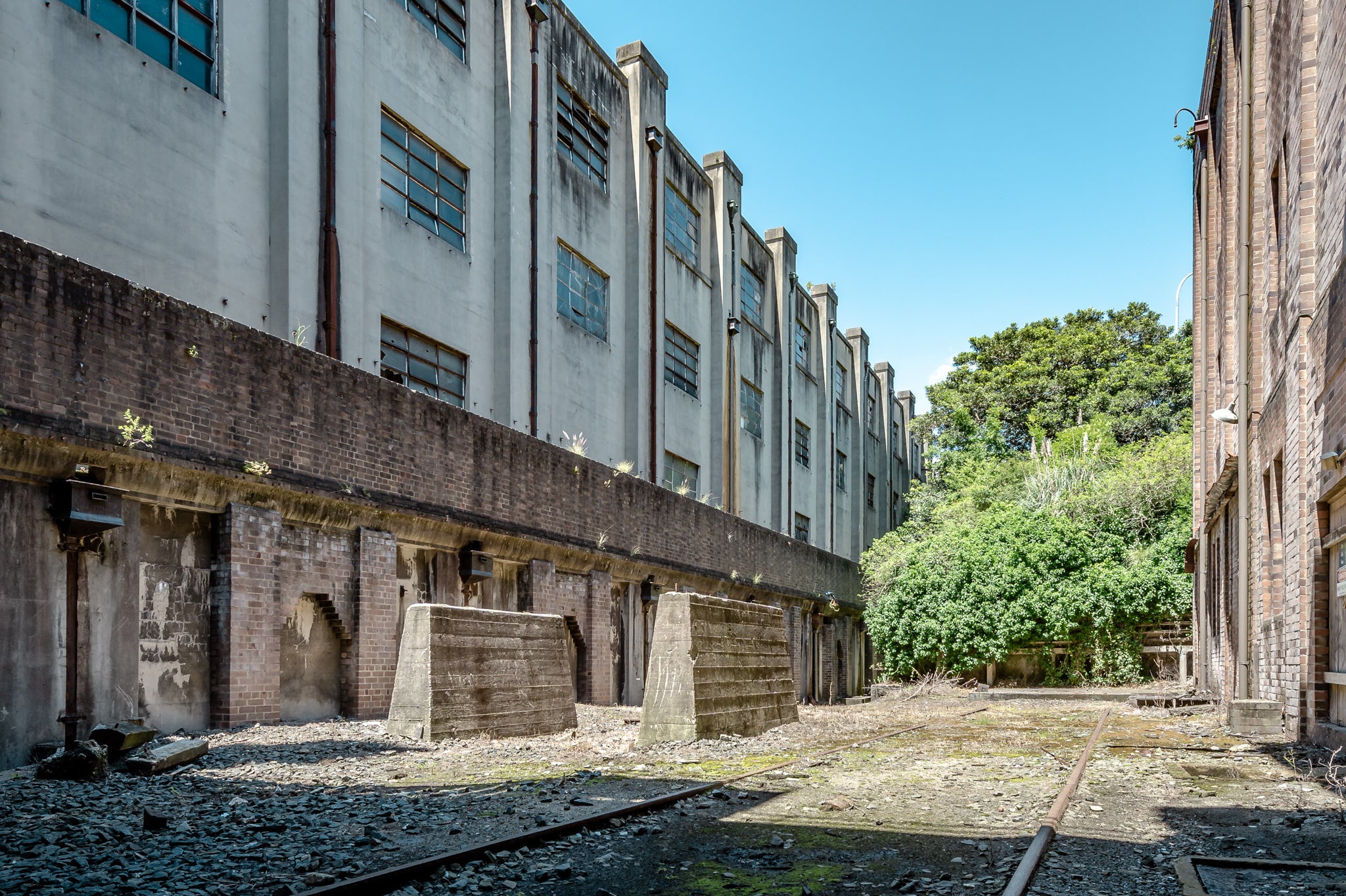 South West Transformer Yard at White Bay Power Station, rail lines run between two industrial buildings, half-buried.