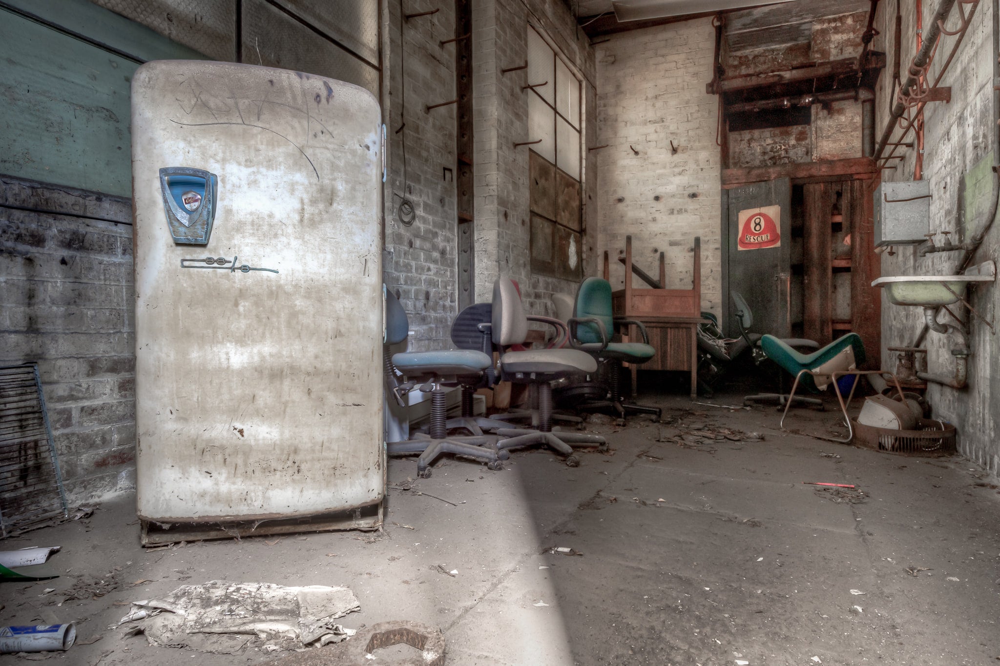 Storage Room at White Bay Power Station, a rounded-top refrigerator stands against bare brick, its chrome badge scratched.