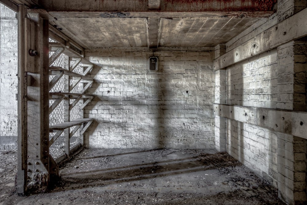 Workshop Storage Cage at White Bay Power Station, a steel staircase with chain-mesh backing rises from a narrow basement.