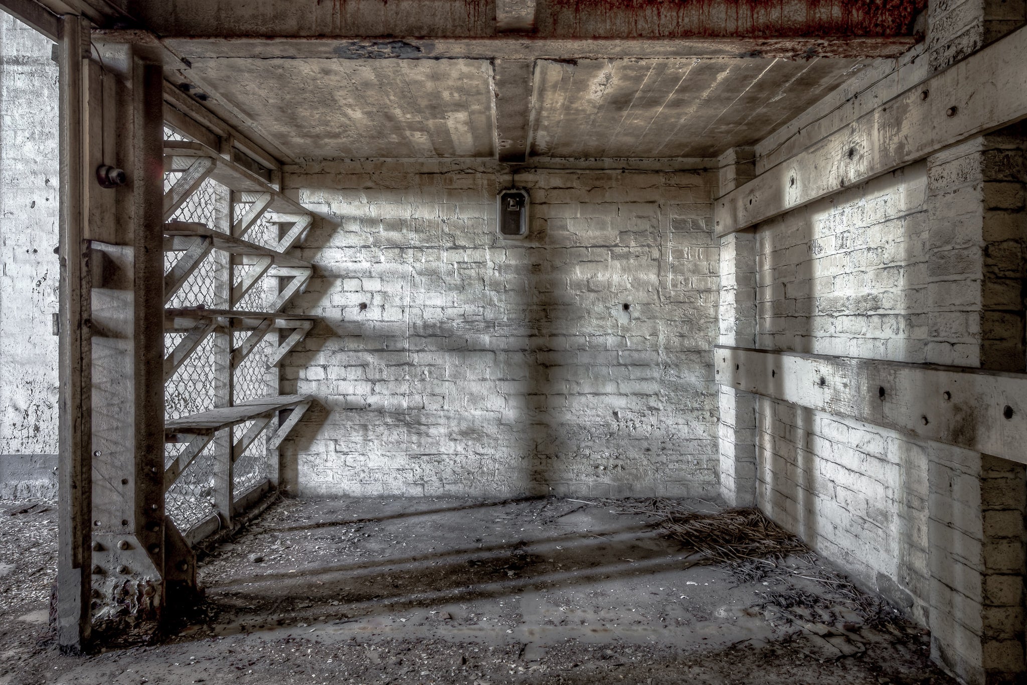 Workshop Storage Cage at White Bay Power Station, a steel staircase with chain-mesh backing rises from a narrow basement.