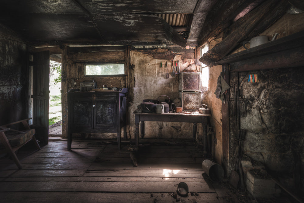 Kitchen at Woolla, a low ceiling of corrugated iron and rough-hewn beams presses down over wide timber floorboards.