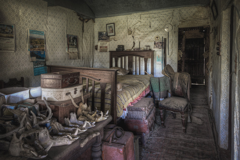 Main Bedroom at Woolla, a timber-framed single bed sits against patterned wallpaper, its woven bedspread still spread flat.