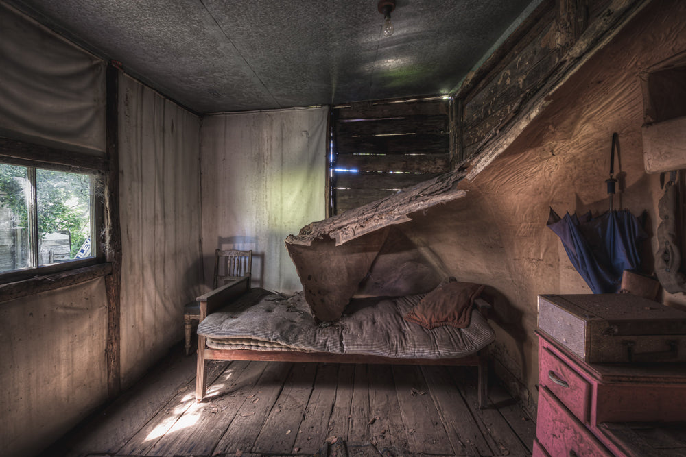 Rear Bedroom at Woolla, a single bed sits against the back wall, its striped mattress sagging under a collapsed sheet.