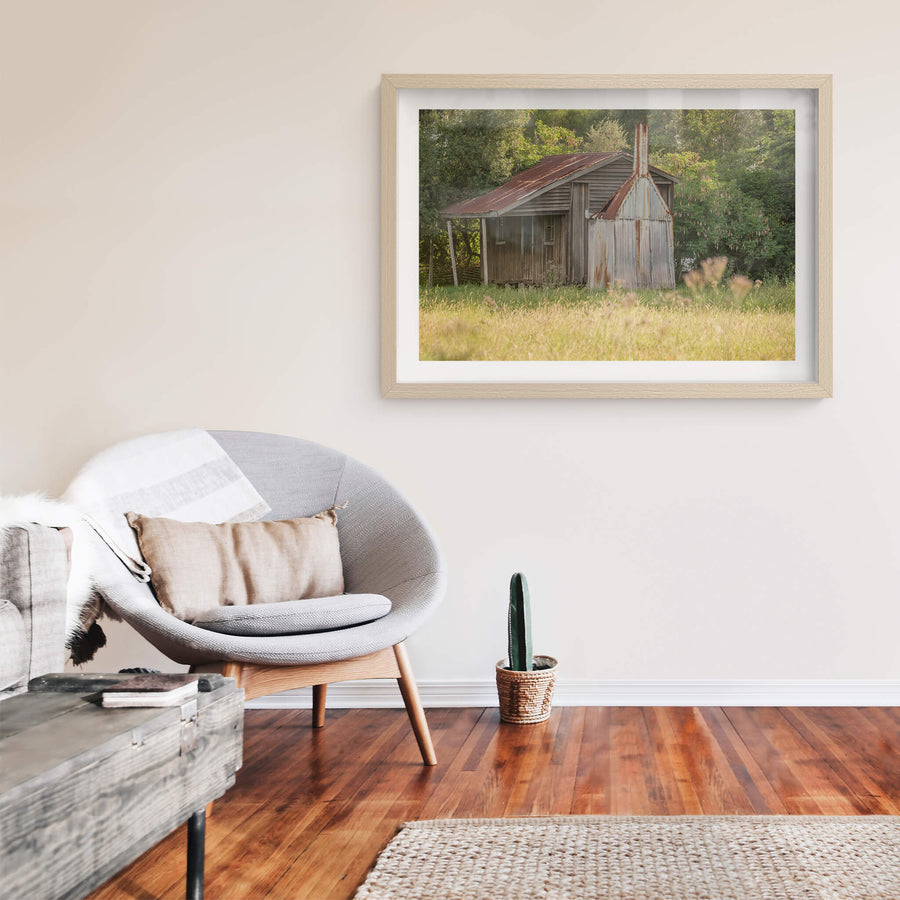 Hunter Hut at A Place to Call Home, a small timber and corrugated iron hut sits at the edge of a grass paddock in late.