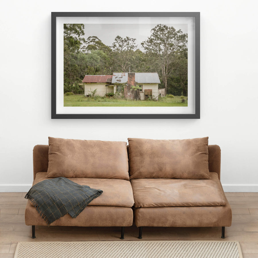 Lochview Cottage at A Place to Call Home, a small weatherboard cottage sits low in a flat green clearing, backed by dense.