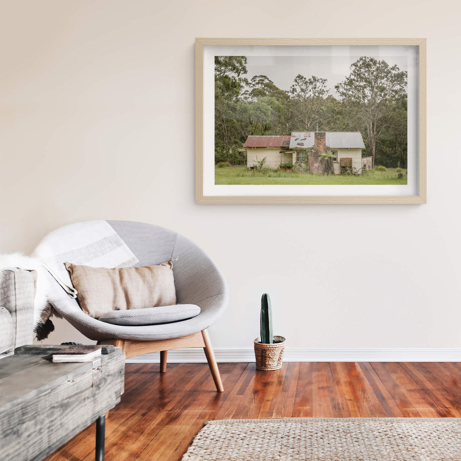 Lochview Cottage at A Place to Call Home, a small weatherboard cottage sits low in a flat green clearing, backed by dense.