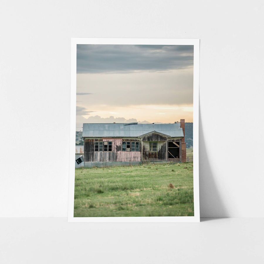 Matong Hut at A Place to Call Home, a weatherboard farmhouse sits low in open green paddock.