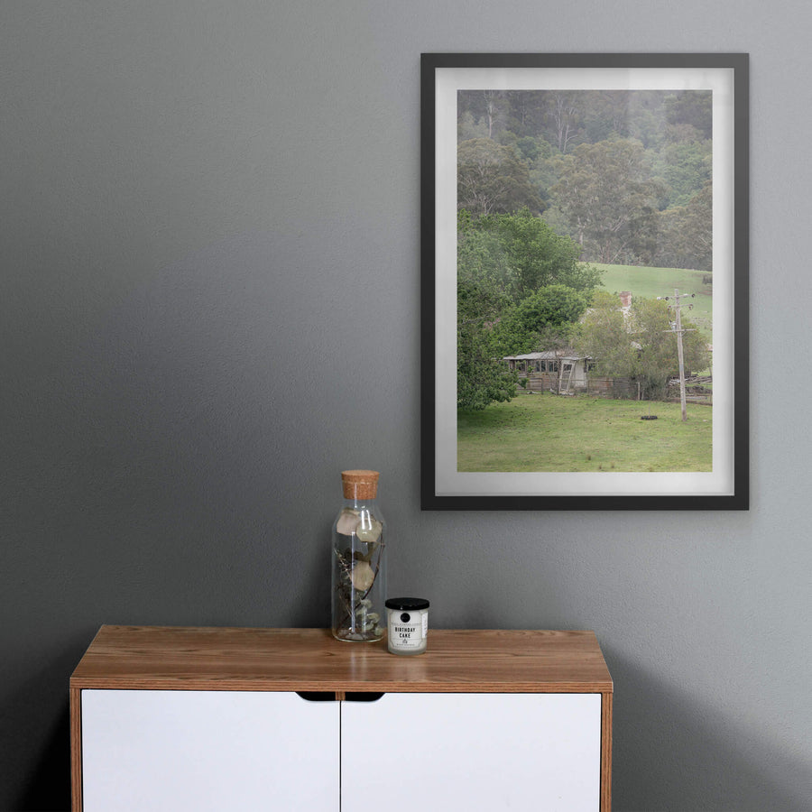 Reclaimed Home at A Place to Call Home, a weatherboard farmhouse sits low in a valley of green pasture, half-swallowed.