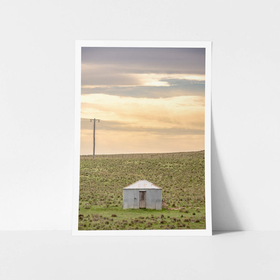 Springfield Drovers Hut at A Place to Call Home, a single corrugated iron hut sits low in open grassland.