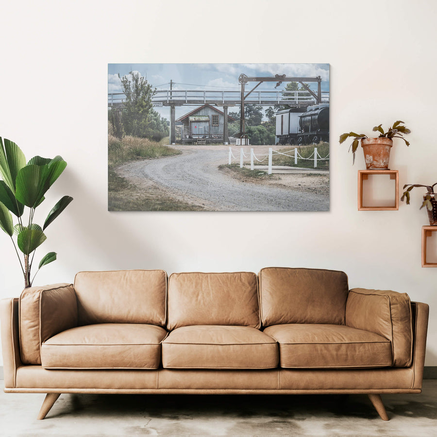 Yard at Bombala Station, a gravel road curves beneath a steel overhead crane and timber footbridge.