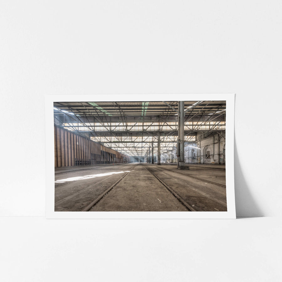Suburban Car Workshop Facing East at Eveleigh Paint Shop, light spills through the sawtooth roof, filtering through layers of steel and glass to cast long shadows across the dust-laden floor.