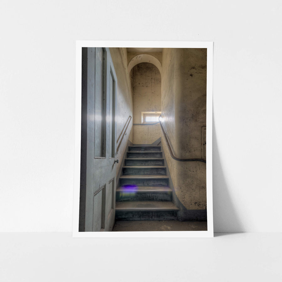 Flare at Female Ward 9 & 10, a narrow stairwell climbs between plaster walls stained grey and ochre with damp.
