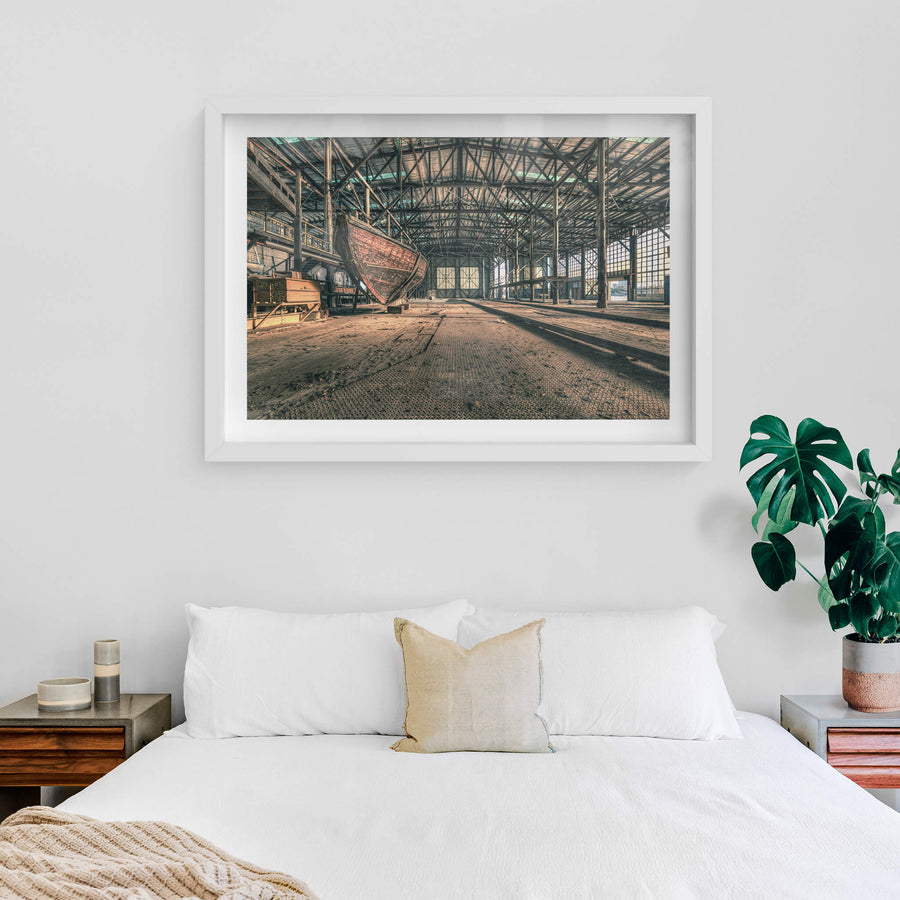 Checkerplate at Halvorsens Boat Yard, a timber hull sits propped on blocks inside a vast industrial shed.