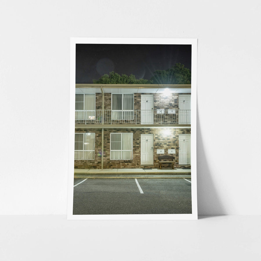 Gosford Palms Motor Inn at Hotel Motel 101, two storeys of brown brick and white panel doors face an empty car park.